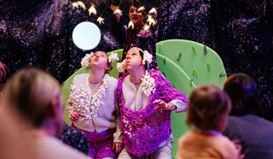 An image showing a scene from the the theatre show "Counting Sheeps" where could be seen three of the actors blowing up in the air towards fairy light