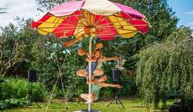 Three individuals attaching themselves to a beach umbrella.
