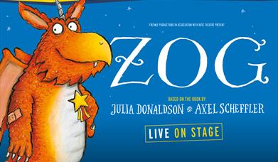 Orange dinosaur cartoon, wearing a star on his chest and a plaster on his elbow. Slightly smiling at camera